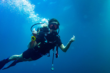 Woman scuba diver showing love sign with her fingers
