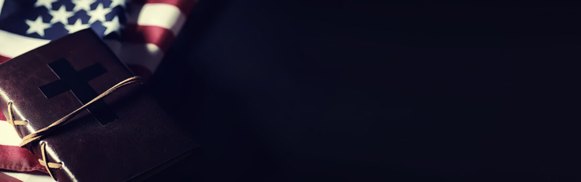 American flag and holy bible book on a mirror background. Symbol of the United States and religion. Bible and striped flag on a black background.