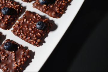Chocolate dessert with nuts and fresh berries. Sweet snack for coffee biscuit in glaze and nut crumbs with fruit.