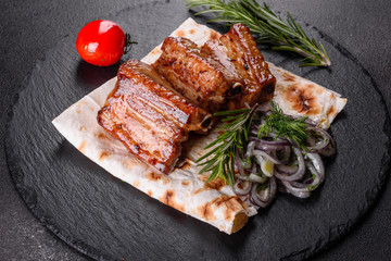 Fried ribs with rosemary, onion, sauce on a concrete background