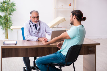 Fototapeta premium Injured young man visiting old doctor