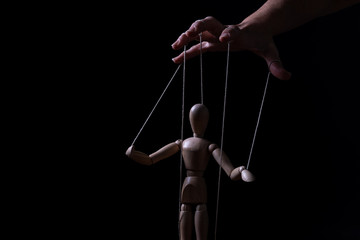 Conceptual image of a hand with strings to control a marionette - 335730510
