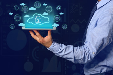 Businessman with tablet computer and hologram projection of cloud storage service against dark background
