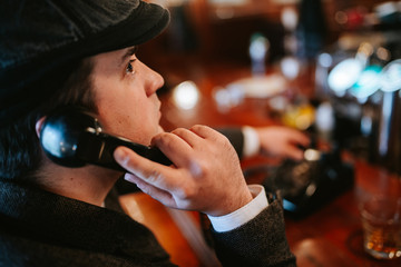 
A young man sits at a bar and talks on an old phone. Business man sitting in cafe after work