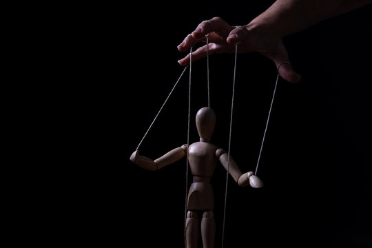 Conceptual image of a hand with strings to control a marionette