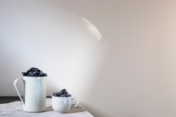 Two aluminum and porcelain cups with honeysuckle are on the table. Still life.