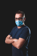 Adult person with protective face mask posing on a black background - social issues with virus and...