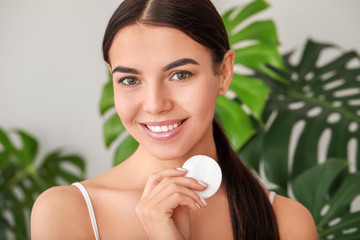 Beautiful young woman with cotton pad at home