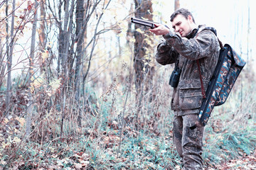 Naklejka premium A man in camouflage and with a hunting rifle in a forest on a spring hunt