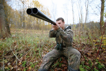 Man in camouflage and with guns in a forest belt on a spring hunt