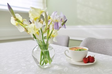 Strawberry tea on table, with vase of irises flowers
