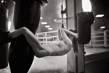 Woman training abs on punching bag, monochrome.