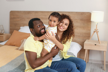 Happy African-American parents with cute baby at home