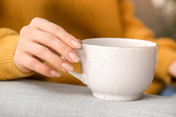 Beautiful young woman drinking tea at home, closeup