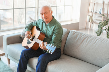 Elderly man playing guitar at home