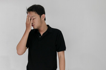 Fototapeta premium Portrait of young asian man isolated on grey background suffering from severe headache, pressing fingers to temples, closing eyes to relieve pain with helpless face expression.