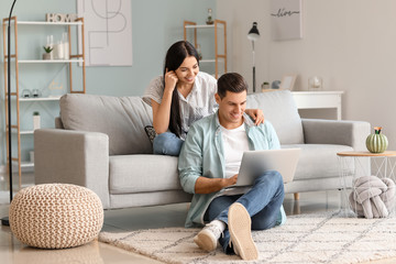 Happy young couple with laptop at home