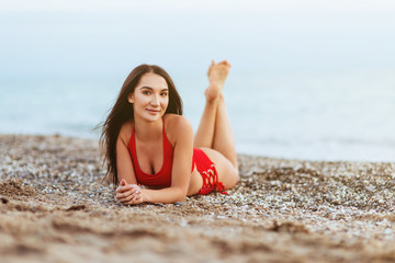 Portrait of attractive young woman in bikini on the beach. Young caucasian female model posing in swimsuit on the sea shore and smiling.