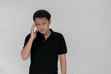 Portrait of young asian man isolated on grey background suffering from severe headache, pressing...