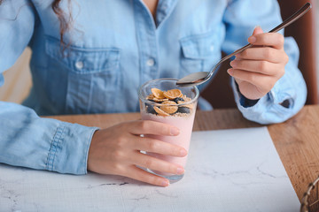 Obraz na płótnie Canvas Young woman eating tasty yogurt in kitchen, closeup