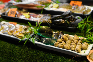Traditional asian night market with delicious seafood and exotic food for tourist. Shell and marinated fish on the counter of a street restaurant for grilling. Night photo under fluorescent light.