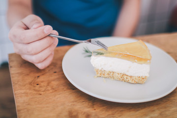 Man wear blue t-shirt sitting in coffee shop eating lemon cheesecake in white plate with folk.Tasty fresh homemade cream cheese sweet cake for breakfast.Eat delicious dessert is good for your mood. 