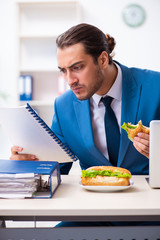 Young male employee having breakfast at workplace