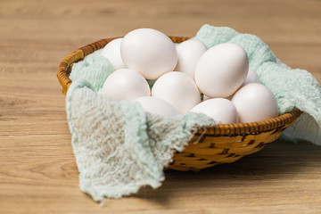 White eggs in a wicker basket with a mint cloth. eggs on a light wooden background