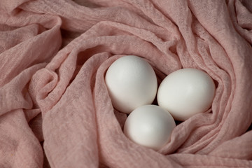 Colorful Easter eggs with spring flowers on a soft pink background with fabric. The view from the top, flat bed.