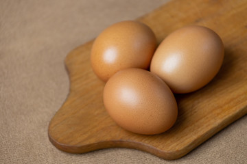 Fresh natural chicken eggs on a wooden stick. Farm brown eggs. On a background of brown fabric