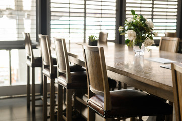 Empty wooden chairs with leather padding are set around tables in restaurant. Cafe closed during covid-2019 quarantine.