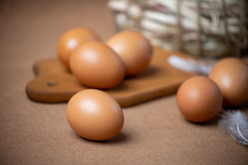 Fresh natural chicken eggs on a brown background with a basket