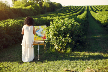 Woman artist painting with oil. Paints in a field