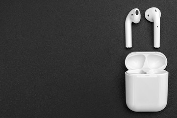 Bluetooth headphones with box on black background. Space for text.