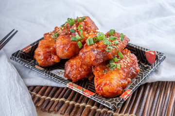 A view of a plate of Asian style spicy chicken wings, in a restaurant or kitchen setting.