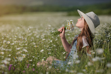 beautiful girl in denim in a camomile field