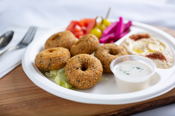 A view of a plate of donut shaped falafel, in a restaurant or kitchen setting.