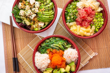 A top down view of several varieties of poke bowls, in a restaurant or kitchen setting. © DAVID