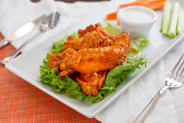 A view of a platter of buffalo wings, in a restaurant or kitchen setting.