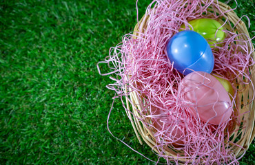 Easter eggs on a basket with grass and green background for happy easter celebration