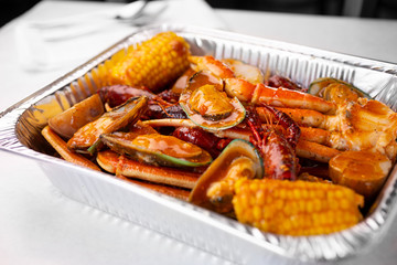 A view of a tin container of seafood boil, in a restaurant or kitchen setting. 