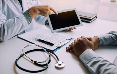 Asian doctor talking the patient at clinic while using the tablet explaining the patient condition...
