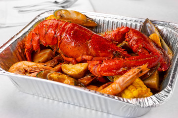 A view of a tin container of lobster boil, in a restaurant or kitchen setting.