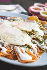 A view of a plate of chilaquiles and eggs, in a restaurant or kitchen setting.