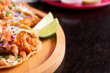 A closeup view of a plate of fish tacos, cut off on the left side of the frame, in a restaurant or kitchen setting.