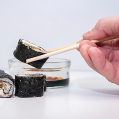 Man eats sushi rolls with chopsticks. Man's hand in the background. Japanese kitchen. Panoramic photo
Rolls of cauliflower, avacado and red fish Salmon. Carbohydrate Keto Diet