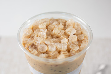 A closeup view of a cup of Vietnamese milk coffee with crushed ice, in a restaurant or kitchen setting.