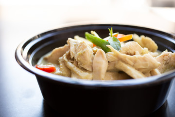 A closeup view of a bowl of green curry, in a restaurant or kitchen setting.