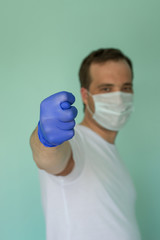 Portrait of attractive man in a medical mask and a glove on a blue background. Pandemic Protection Concept. Stop coronovirus. Covid-19