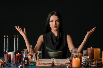 Female alchemist making potion on dark background - obrazy, fototapety, plakaty